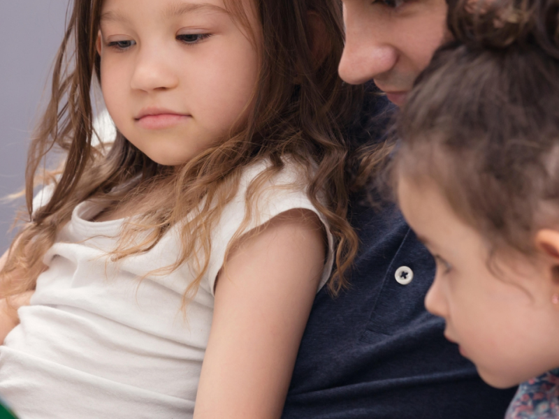 Un padre le lee un cuento a sus hijas